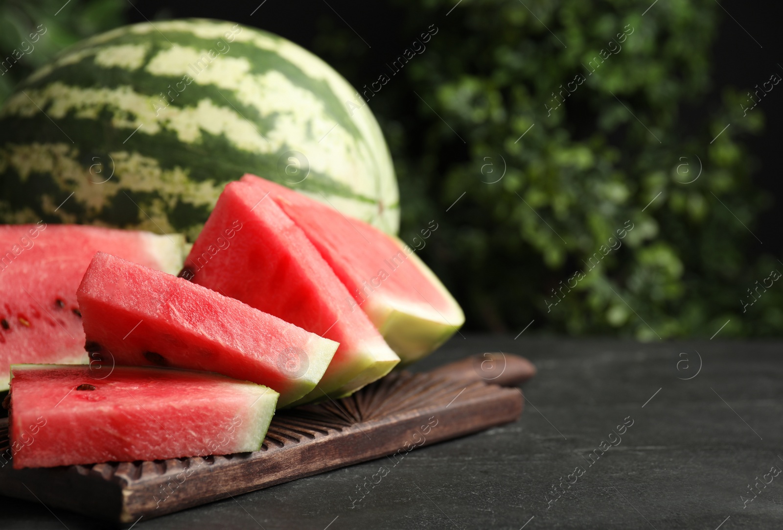 Photo of Whole and cut ripe watermelons on black table. Space for text