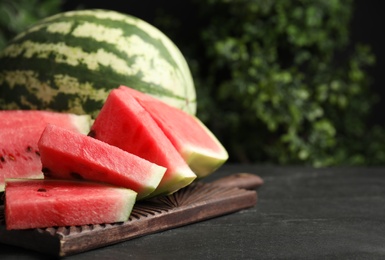 Photo of Whole and cut ripe watermelons on black table. Space for text