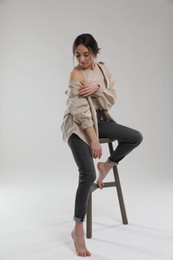 Portrait of beautiful woman sitting on chair against light grey background