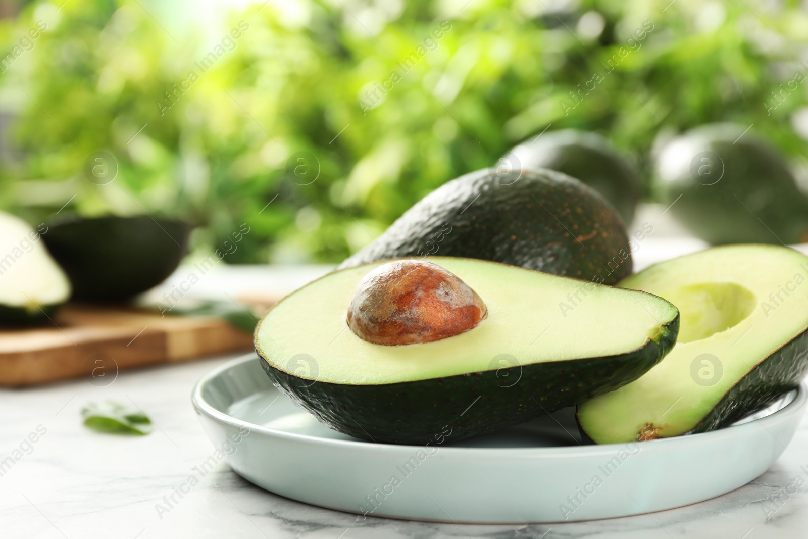 Photo of Delicious ripe avocados on table against blurred background