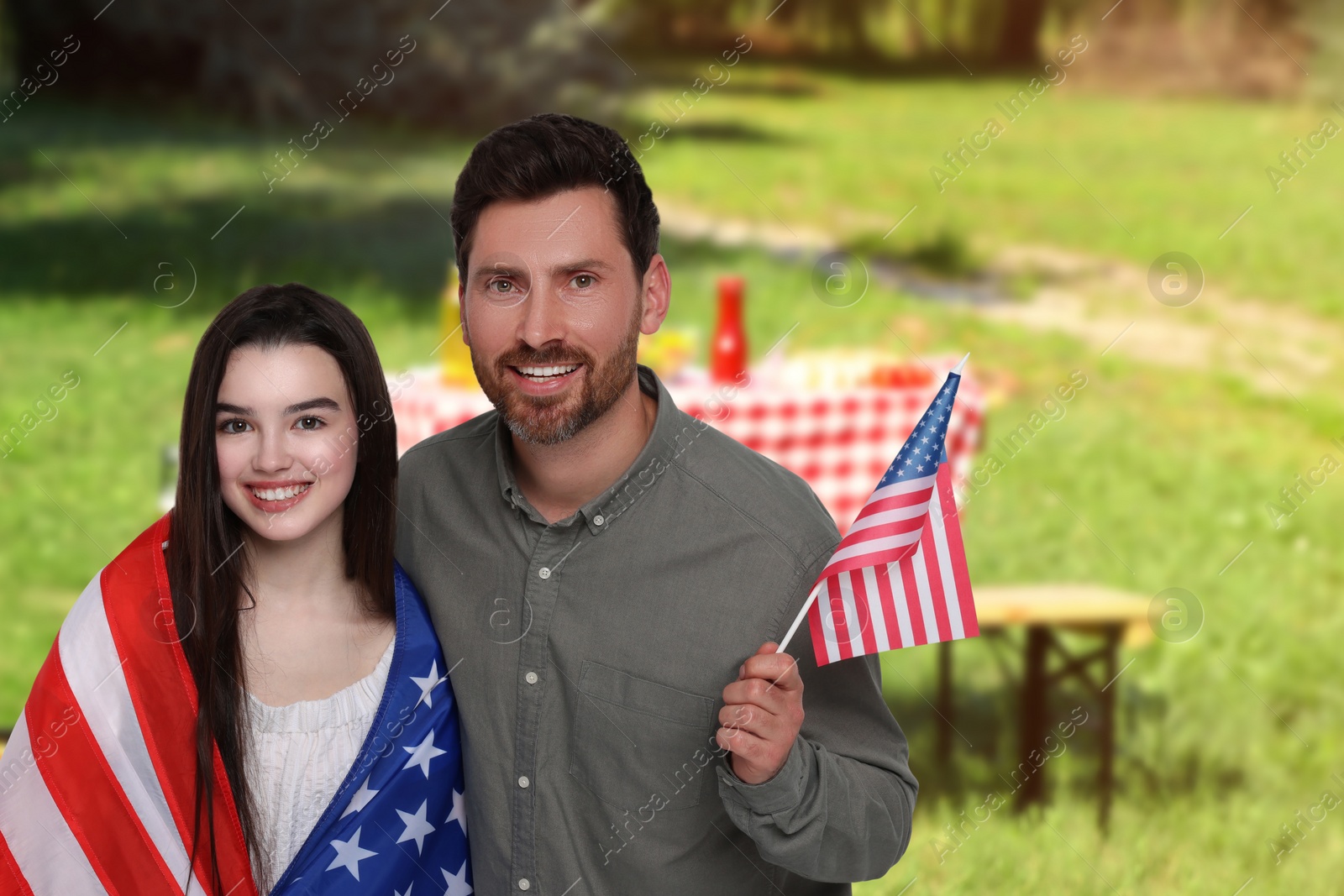 Image of 4th of July - Independence day of America. Happy father and daughter with national flags of United States having picnic in park