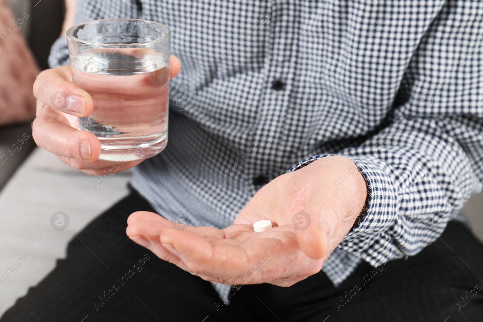 Photo of Senior man holding pill and glass of water, closeup