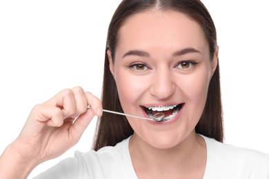 Woman with braces holding dental mirror on white background