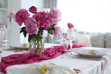 Photo of Beautiful table setting with pink peonies in dining room