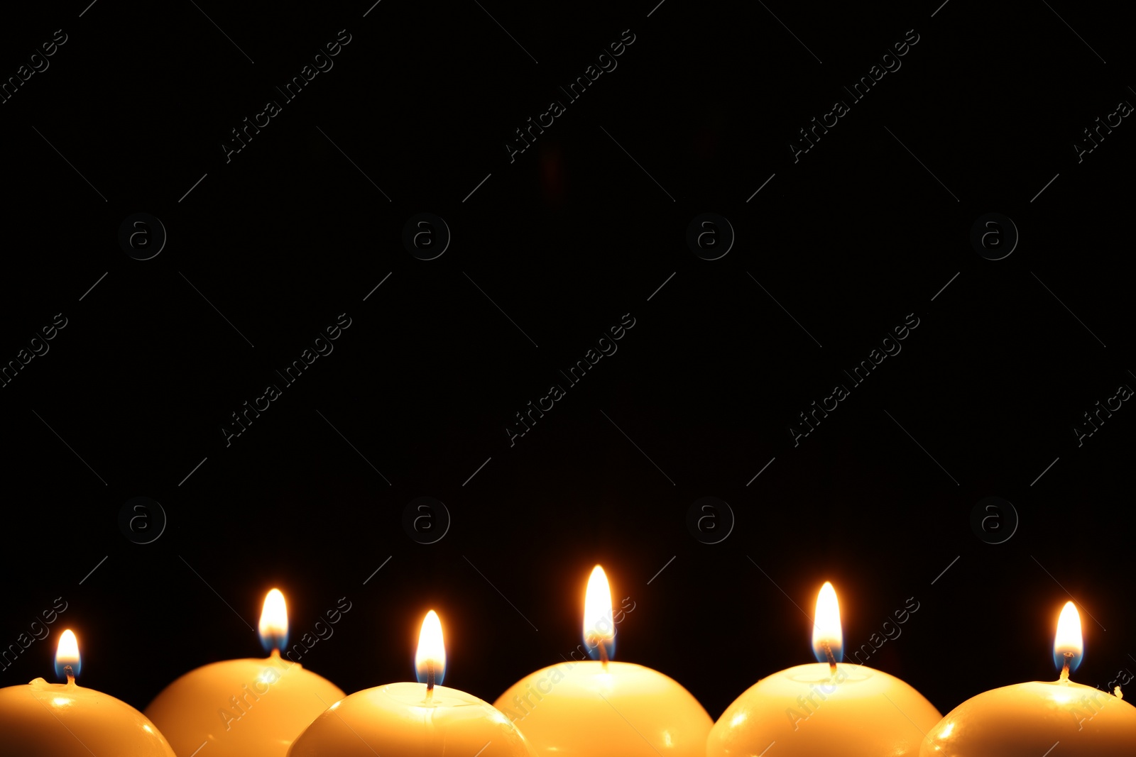 Photo of Many burning wax candles on black background, closeup. Space for text