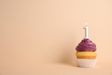 Photo of Birthday cupcake with number one candle on beige background, space for text