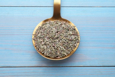 Metal spoon with dried thyme on light blue wooden table, closeup