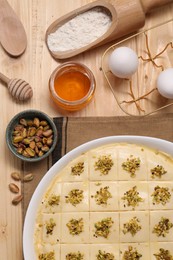 Photo of Making delicious baklava. Raw dough with ingredients on wooden table, flat lay
