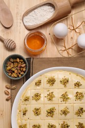 Making delicious baklava. Raw dough with ingredients on wooden table, flat lay