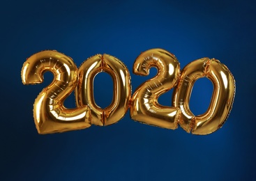 Photo of Golden balloons for party decoration on blue background. 2020 New Year celebration