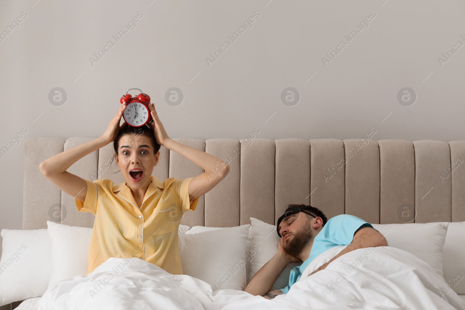 Photo of Emotional woman and sleeping man in bedroom. Being late concept