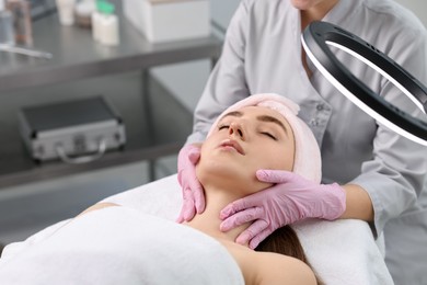 Photo of Cosmetologist making face massage to client in clinic, closeup. Space for text