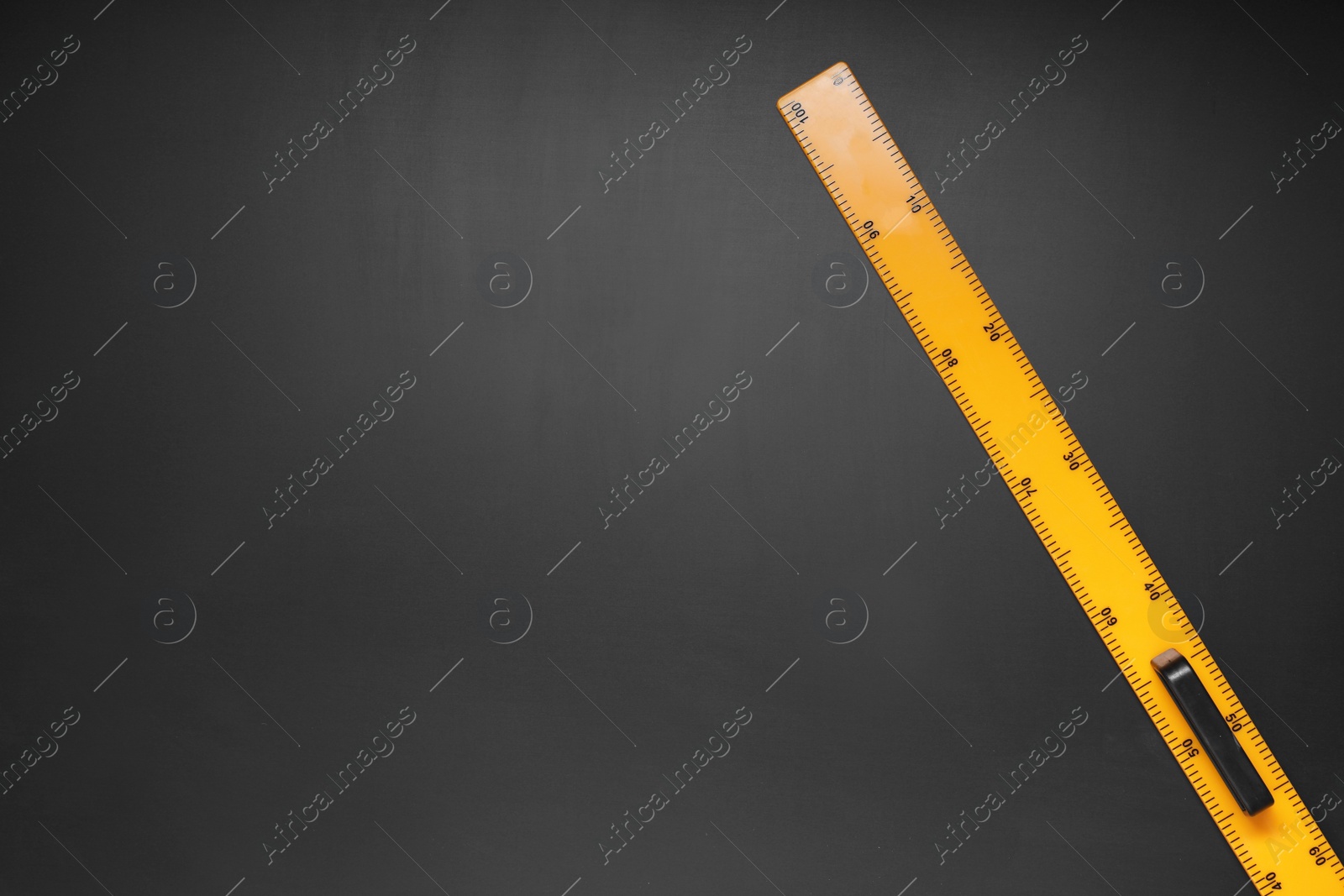 Photo of Yellow school ruler on blackboard, top view. Space for text