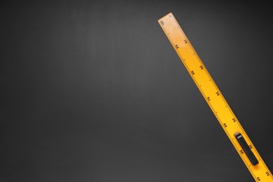 Photo of Yellow school ruler on blackboard, top view. Space for text