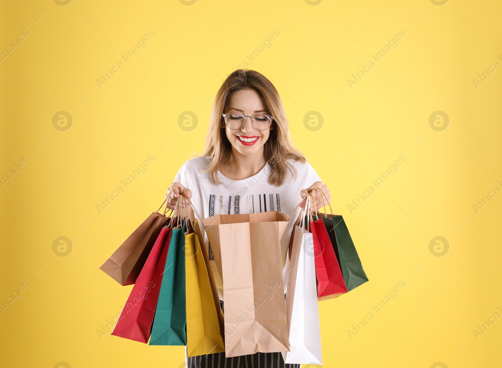 Photo of Beautiful young woman with shopping bags on color background