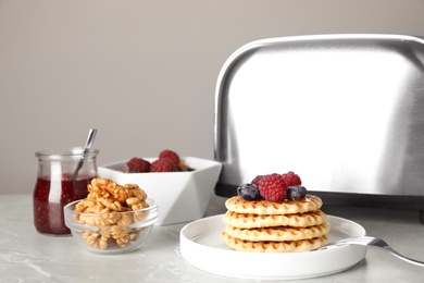 Delicious breakfast with waffles and berries served on light marble table against grey background