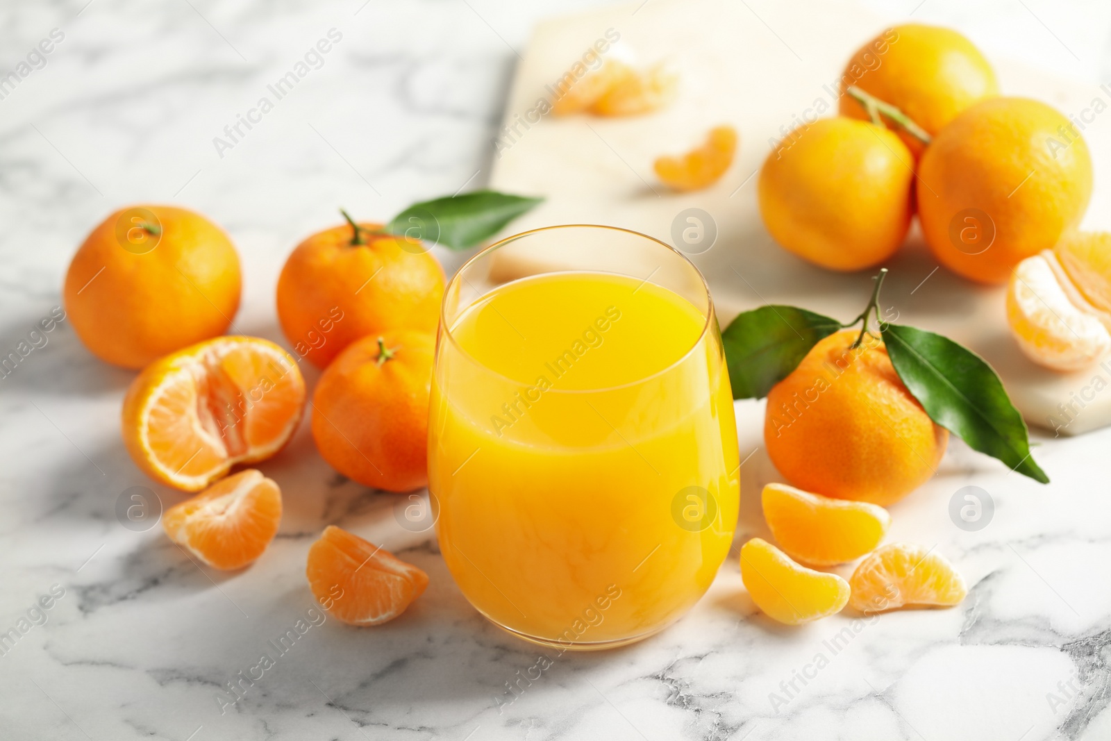 Photo of Glass of fresh tangerine juice and fruits on marble table