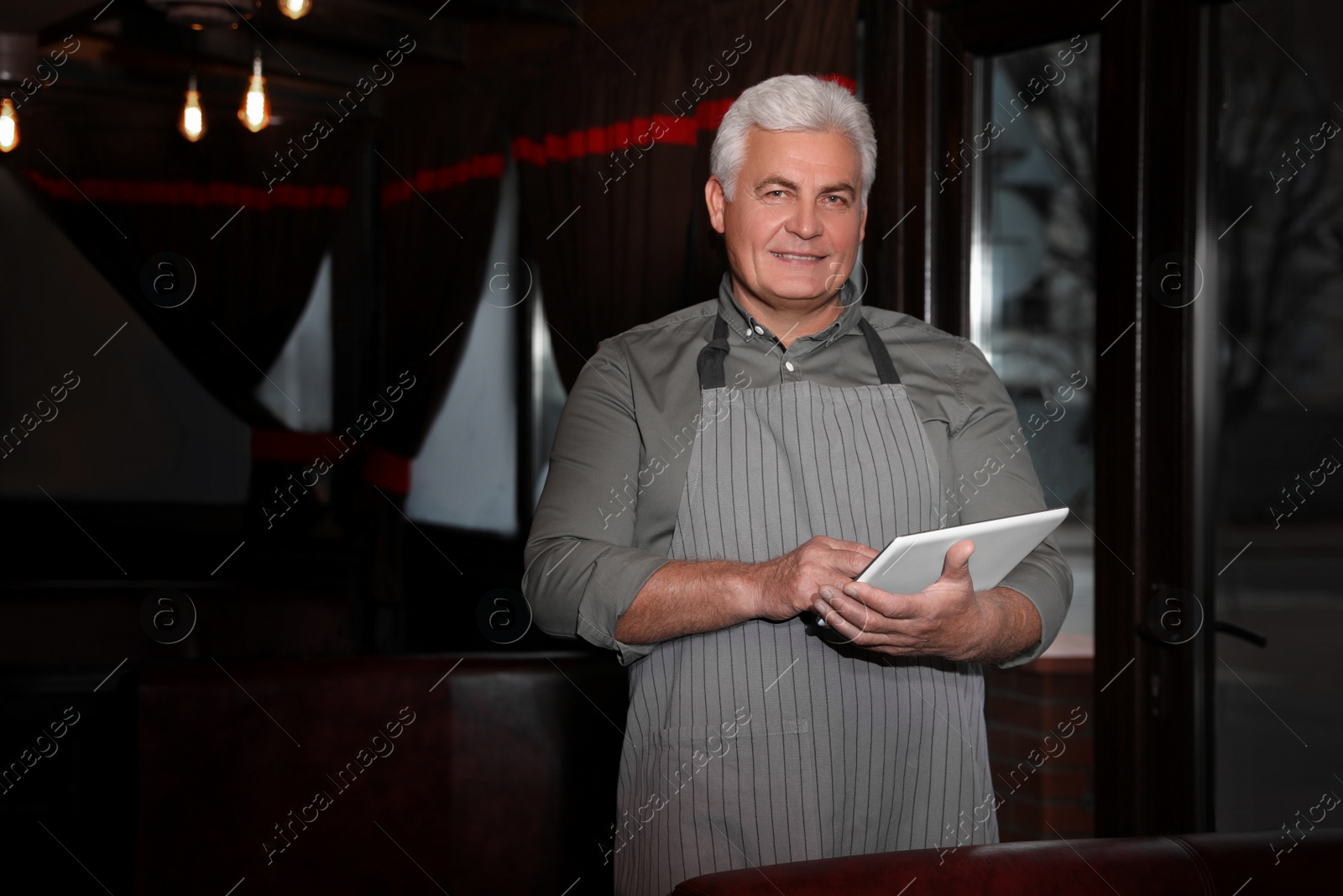 Photo of Senior business owner with tablet in his restaurant