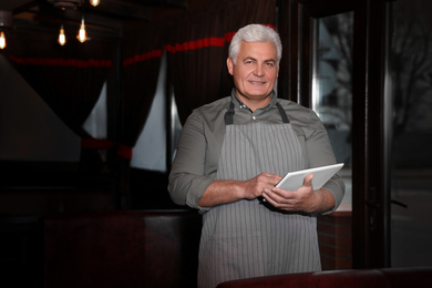 Photo of Senior business owner with tablet in his restaurant