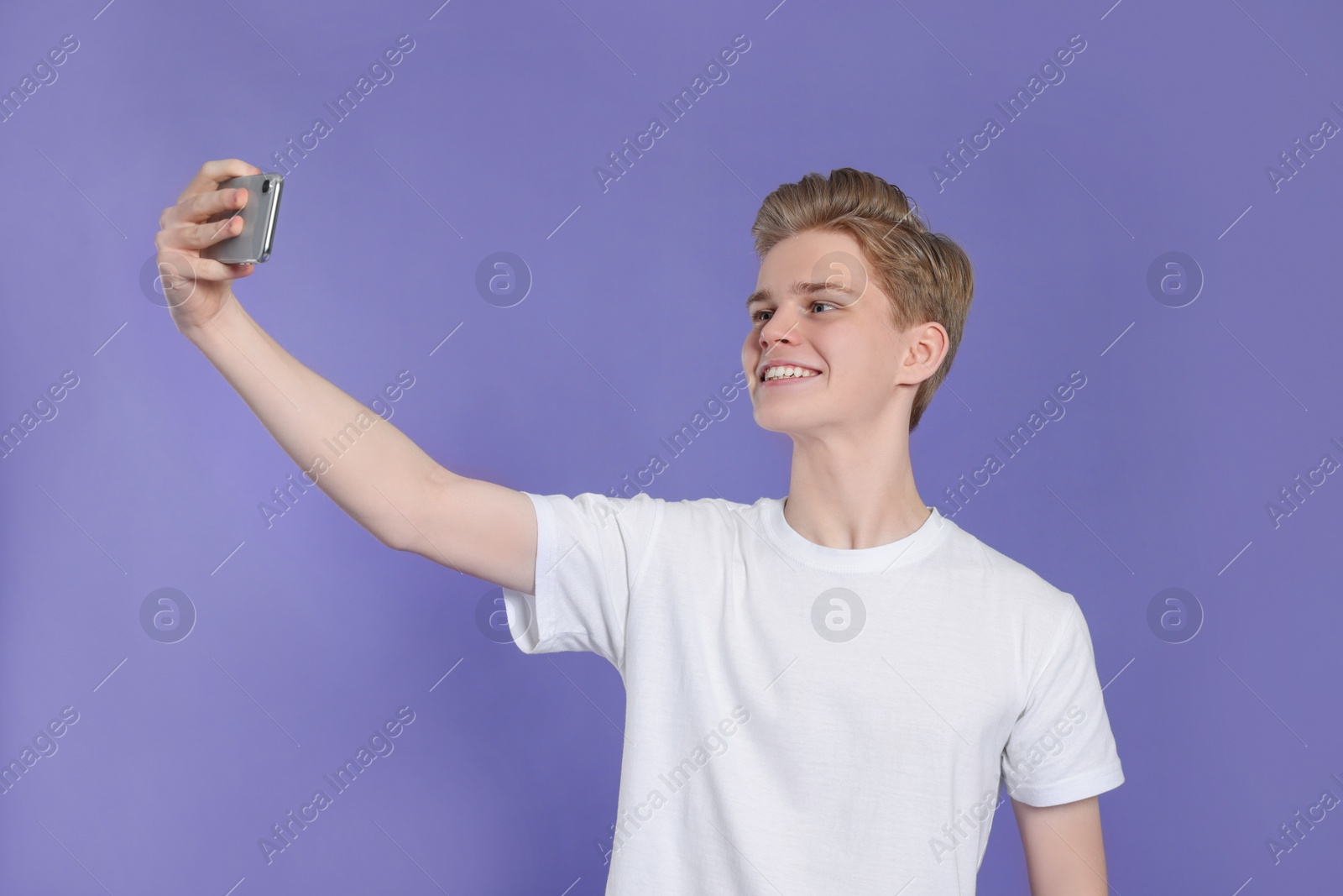 Photo of Teenage boy taking selfie on purple background