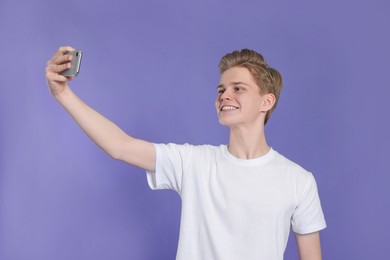 Photo of Teenage boy taking selfie on purple background