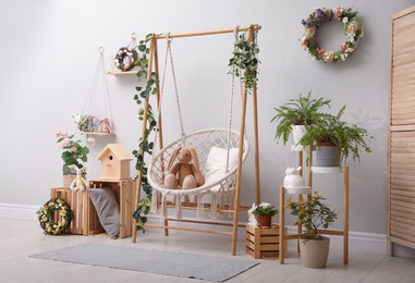 Photo of Easter photo zone with floral decor and swing chair indoors