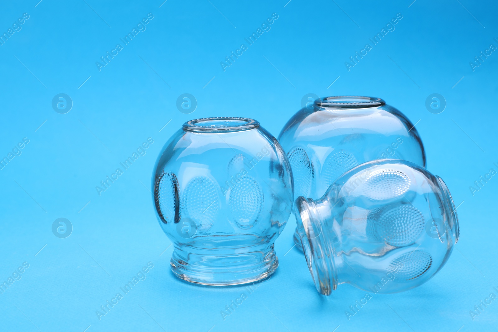 Photo of Glass cups on light blue background, closeup with space for text. Cupping therapy
