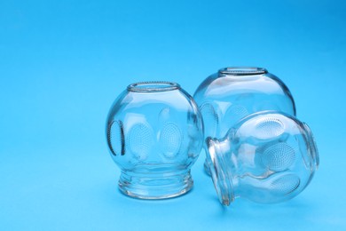 Photo of Glass cups on light blue background, closeup with space for text. Cupping therapy