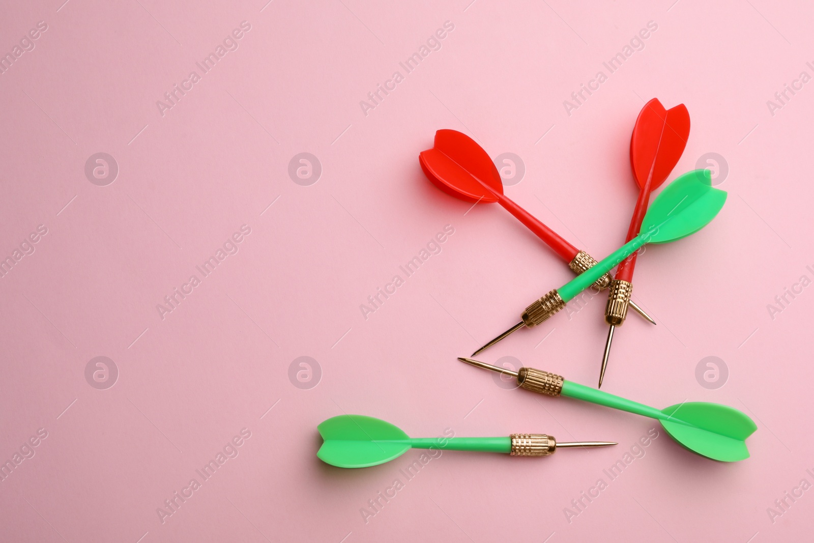 Photo of Plastic dart arrows on pink background, flat lay with space for text