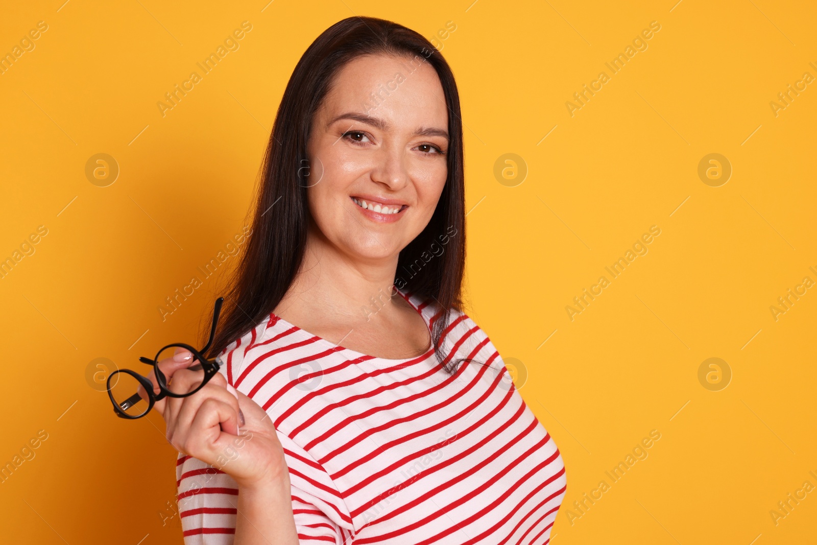 Photo of Beautiful overweight woman with charming smile on yellow background