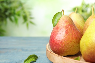 Ripe juicy pears on blue wooden table against blurred background, closeup. Space for text