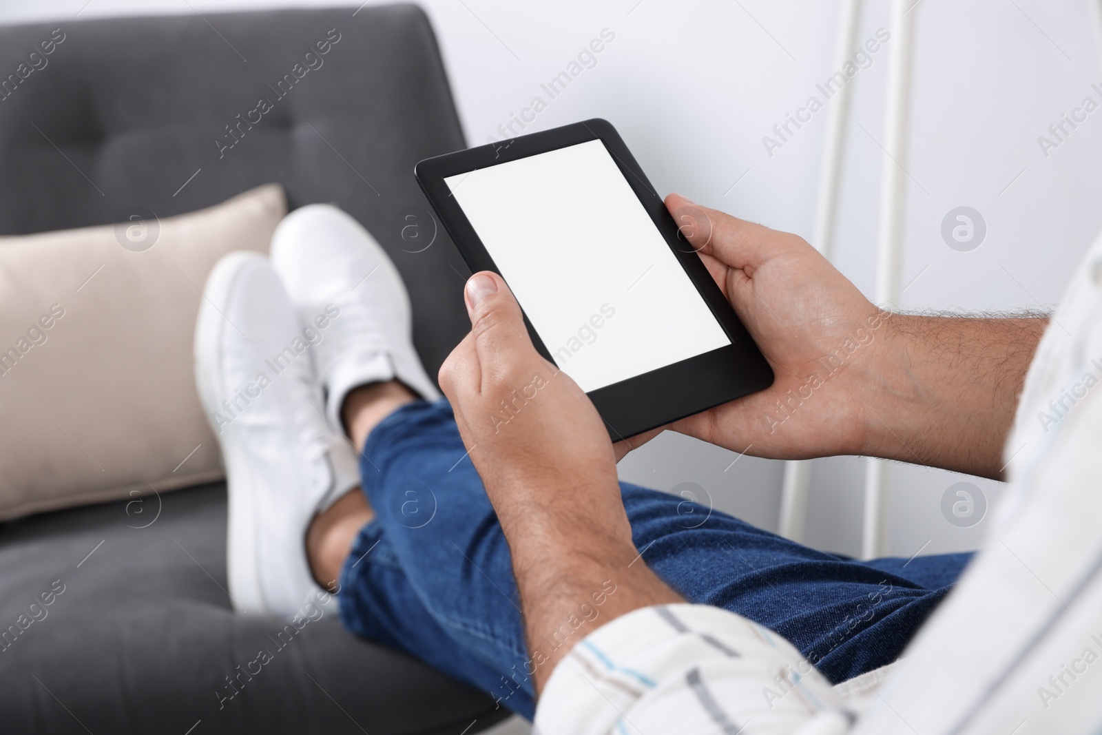 Photo of Man using e-book reader indoors, closeup view