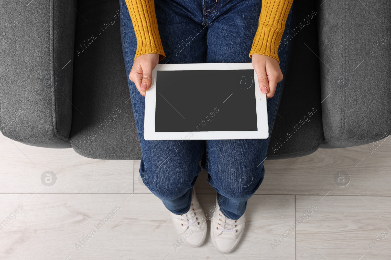 Photo of Woman working with tablet in armchair, top view