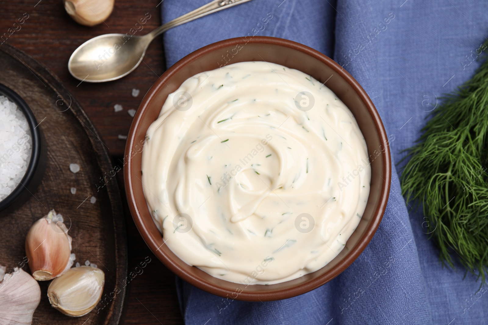 Photo of Tasty creamy dill sauce and ingredients on wooden table, flat lay