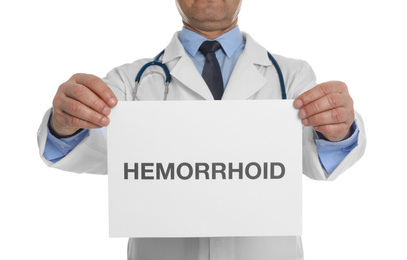 Doctor holding sign with word HEMORRHOID on white background, closeup