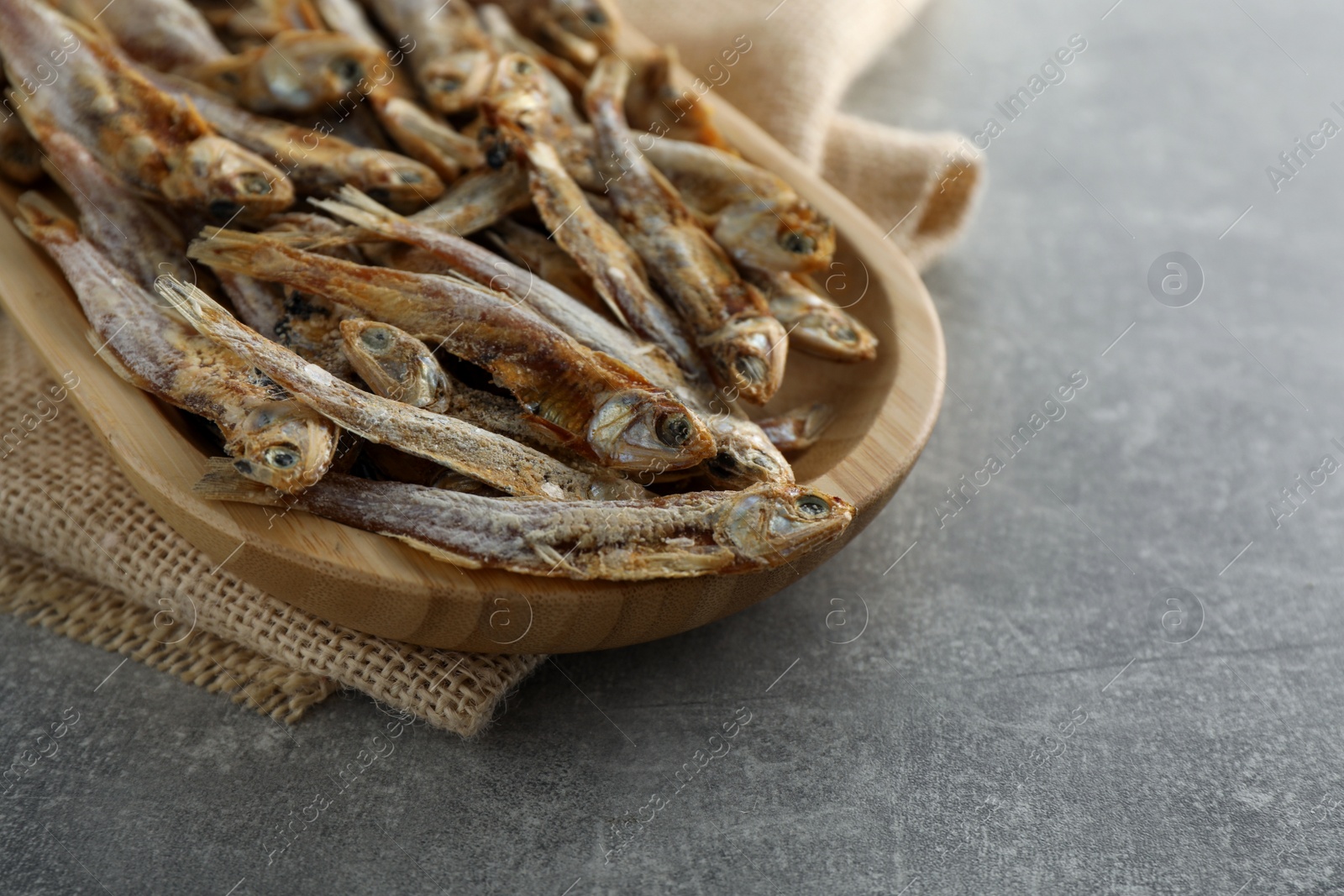 Photo of Delicious dried anchovies on grey table, closeup