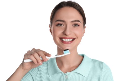 Photo of Young woman holding brush with charcoal toothpaste on white background