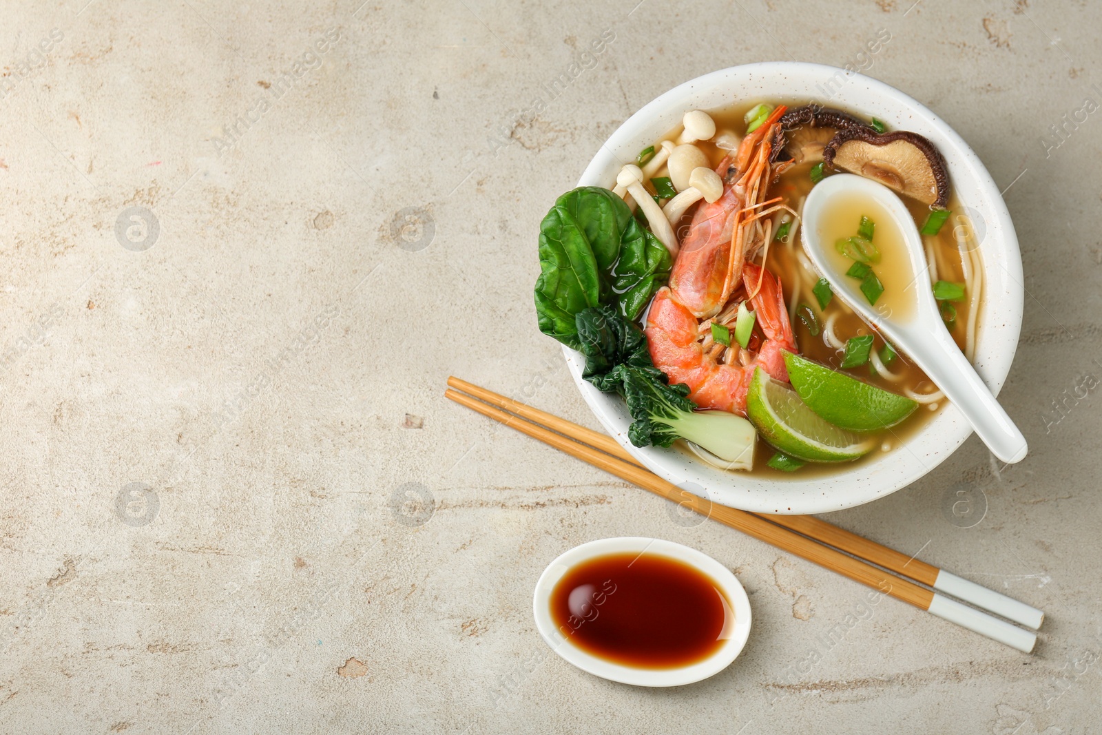 Photo of Delicious ramen with shrimps and mushrooms in bowl served on light textured table, flat lay and space for text. Noodle soup