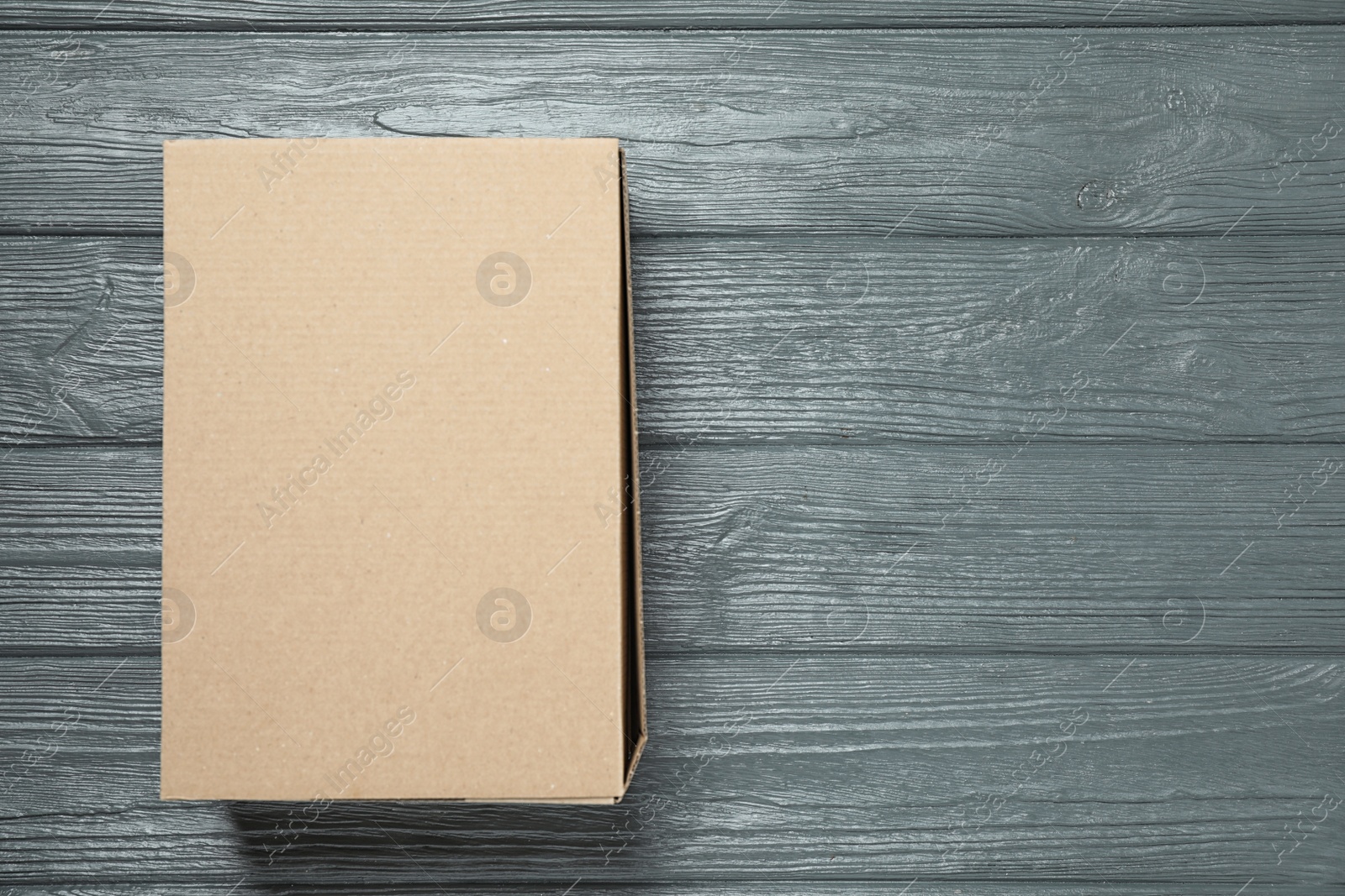 Photo of Closed cardboard box on grey wooden table, top view. Space for text