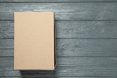 Closed cardboard box on grey wooden table, top view. Space for text