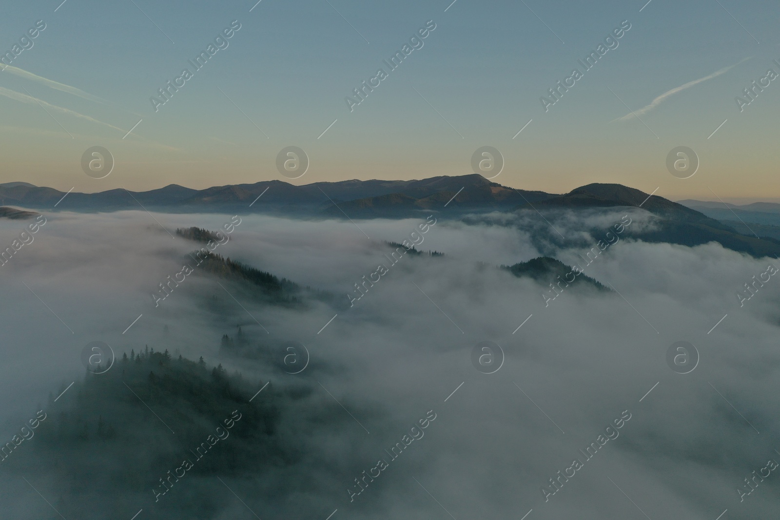 Photo of Aerial view of beautiful mountains covered with fluffy clouds in morning