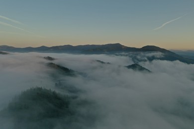 Photo of Aerial view of beautiful mountains covered with fluffy clouds in morning
