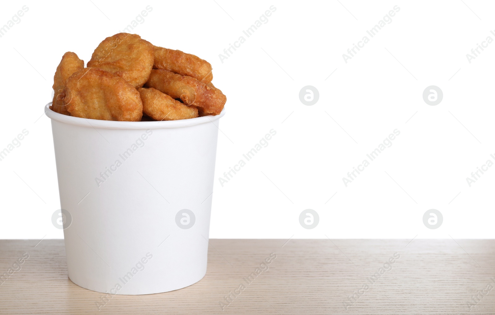 Photo of Bucket with tasty chicken nuggets on wooden table against white background. Space for text