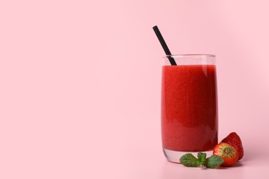 Glass with delicious berry smoothie and fresh strawberries on pink background. Space for text