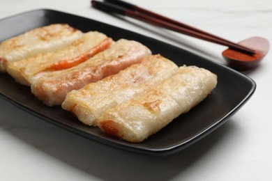 Photo of Delicious fried spring rolls and chopsticks on white table, closeup