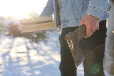 Photo of Man with axe and wood outdoors on sunny winter day, closeup. Space for text