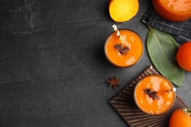 Photo of Tasty persimmon smoothie with anise and fresh fruits on black table, flat lay. Space for text