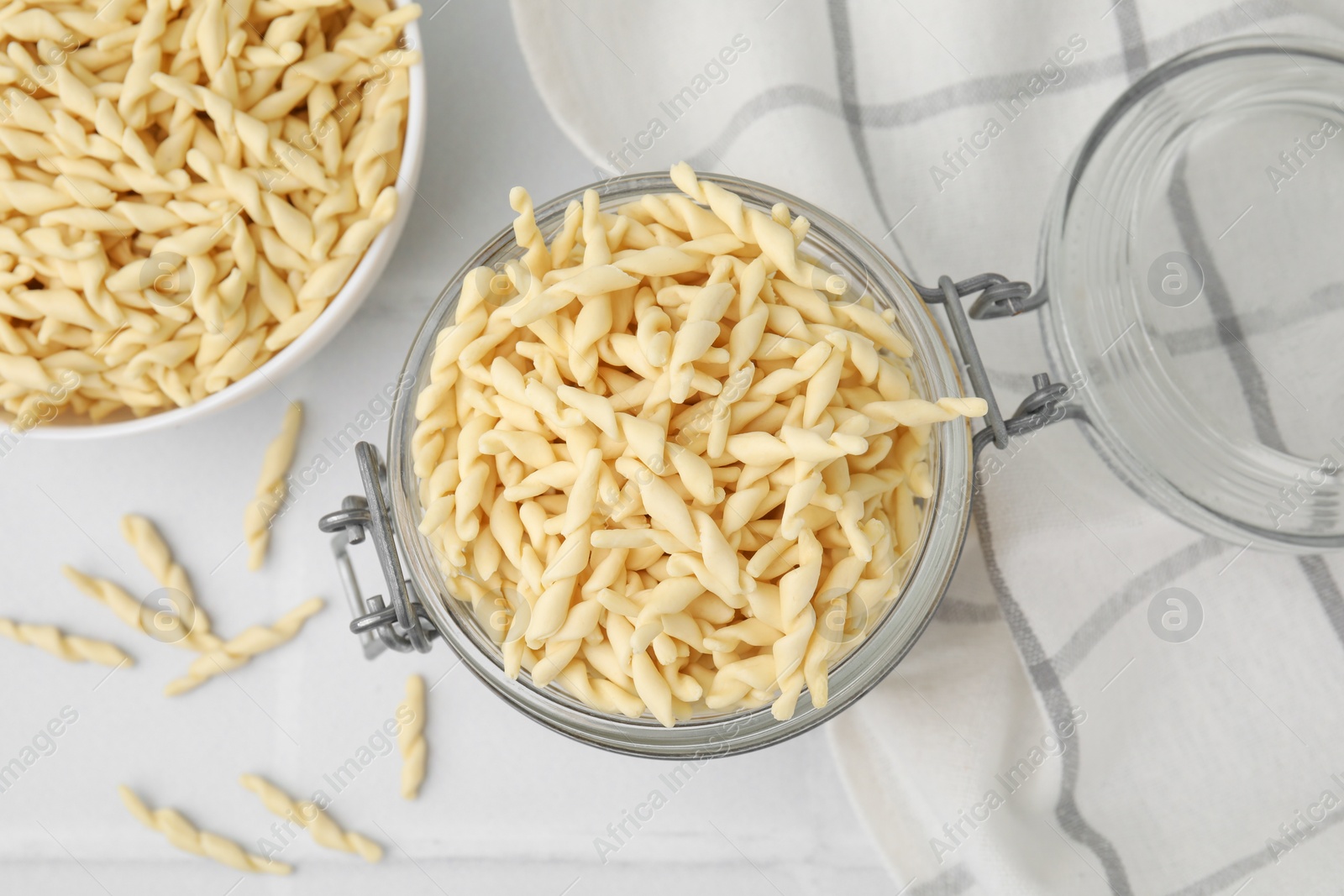 Photo of Uncooked trofie pasta on white tiled table, flat lay