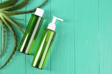 Photo of Bottles of cosmetic gel with aloe extract and fresh leaves on light green wooden table, flat lay. Space for text