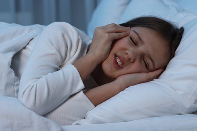 Little girl suffering from headache in bed at night